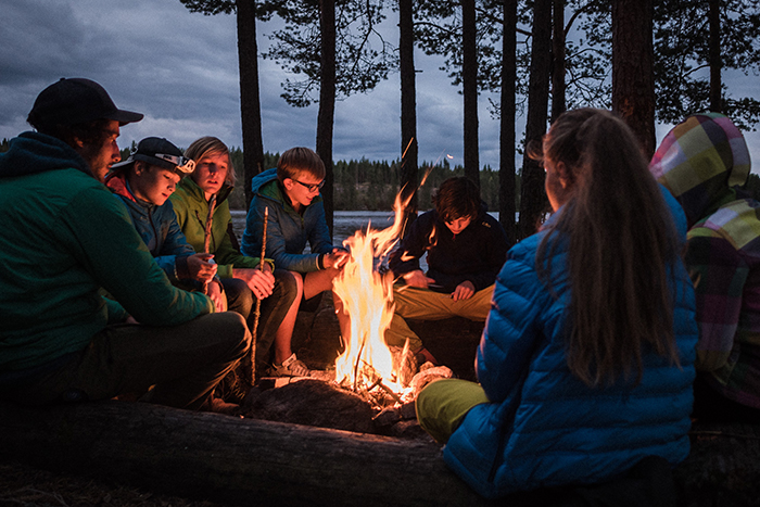 Einige Kinder sitzen um ein Lagerfeuer.