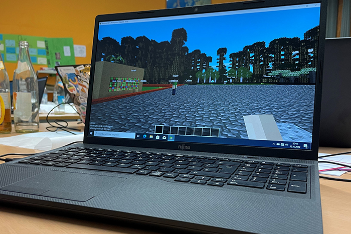 Ein Laptop auf dessen Bildschrim das Minetest-Spiel zu sehen ist