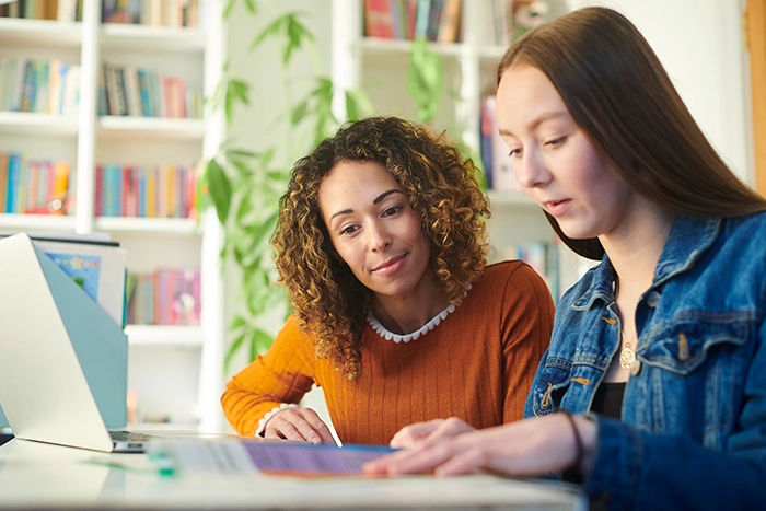 Zwei junge Frauen sitzen gemeinsam vor einem Laptop