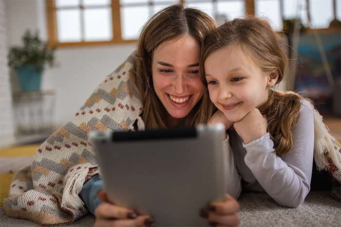 Mutter und Tochter sitzen vor dem Tablet.