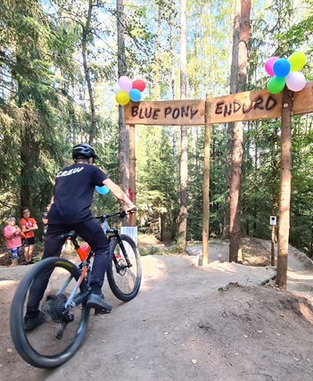 Eine Kind steht mit seinem Mountainbike auf einer Radstrecke im Wald