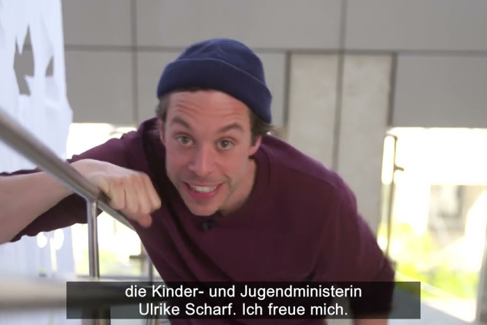 Tobi Krell lehnt lachend an einem Treppengeländer