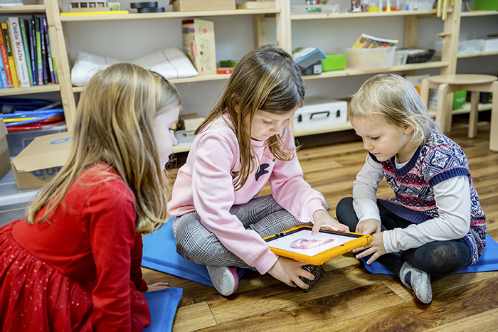 Drei Kinder schauen gemeinsam auf ein Tablet. 